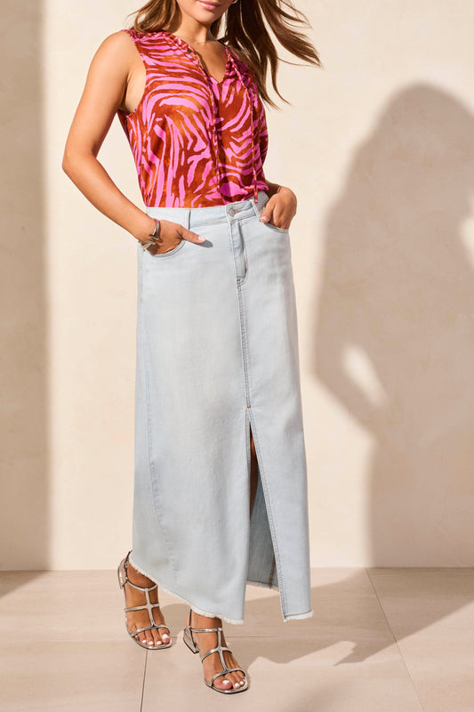 A woman models a chic look in a sleeveless pink and orange blouse, Tribal’s Denim Skirt with Pockets featuring a front slit, styled with silver strappy sandals.