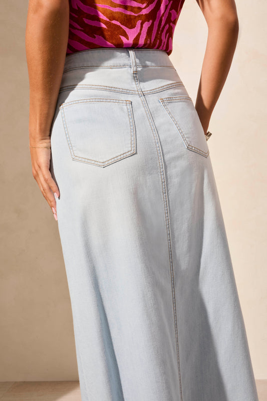 A woman models a chic look in a sleeveless pink and orange blouse, Tribal’s Denim Skirt with Pockets featuring a front slit, styled with silver strappy sandals.
