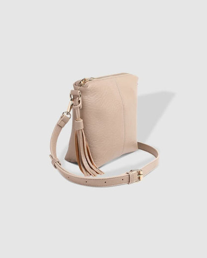 A person in a striped sleeveless top and pleated skirt carries the Louenhide Kasey Textured Crossbody Bag, featuring a wide strap and tassel.
