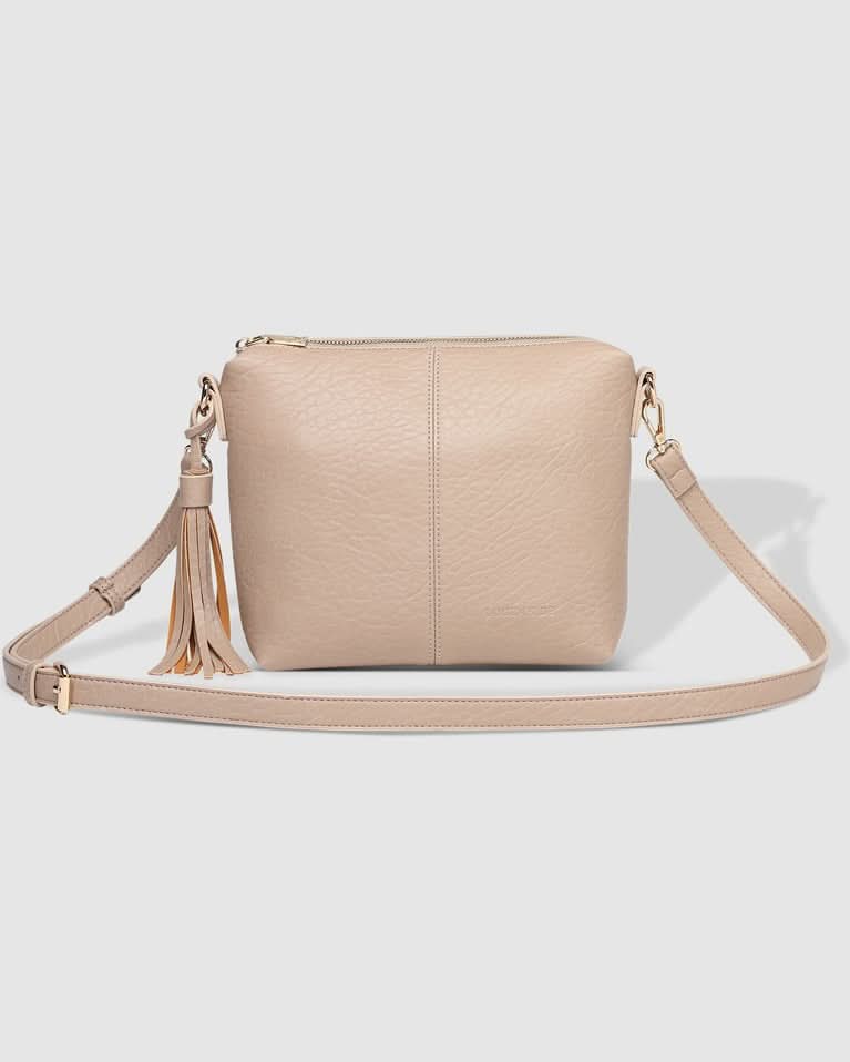 A person in a striped sleeveless top and pleated skirt carries the Louenhide Kasey Textured Crossbody Bag, featuring a wide strap and tassel.